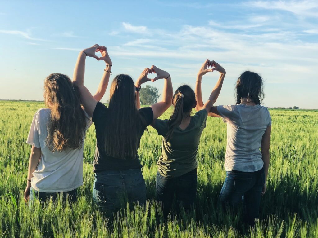 Four women with their hands together to form a love heart shape. Image used to support International Women’s Day 2023