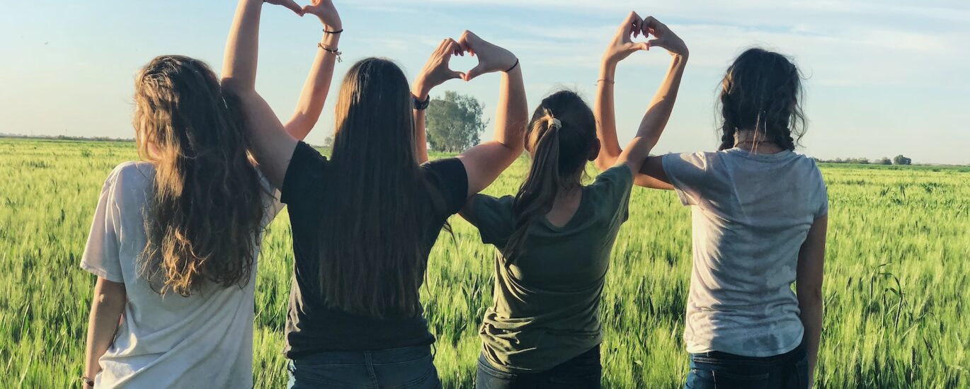 Four women with their hands together to form a love heart shape. Image used to support International Women’s Day 2023